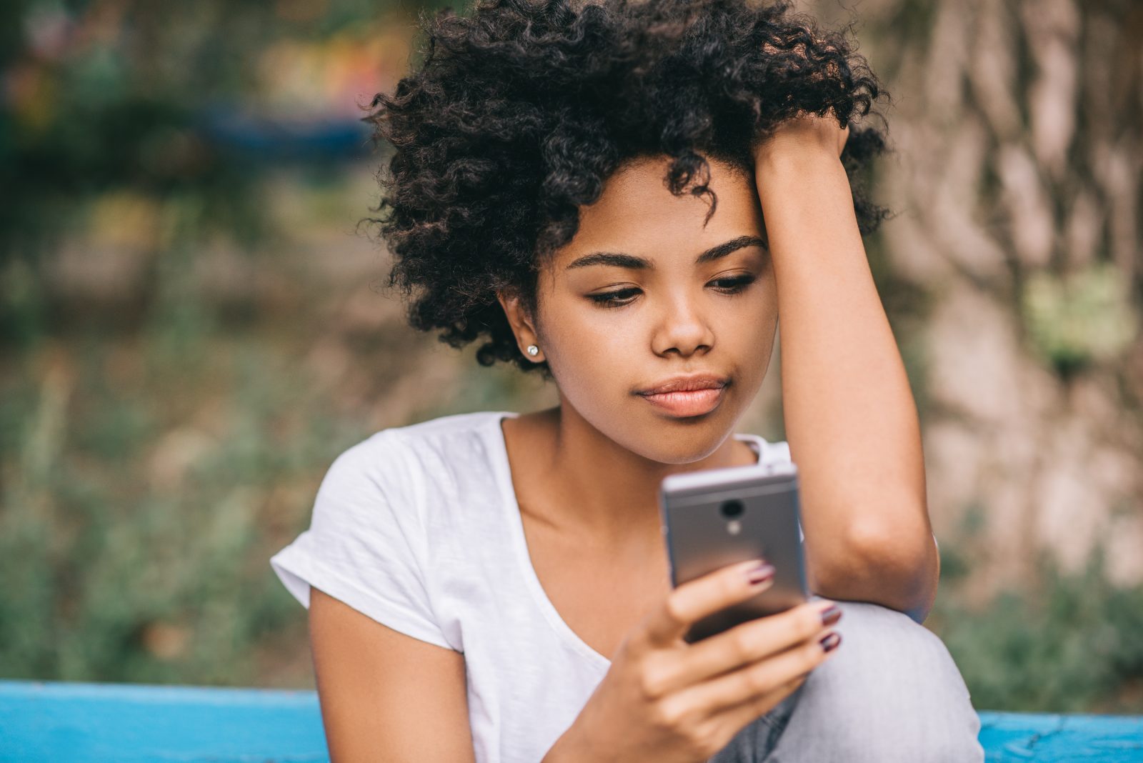 Beautiful African American Female Student Sitting On Bench Outdo